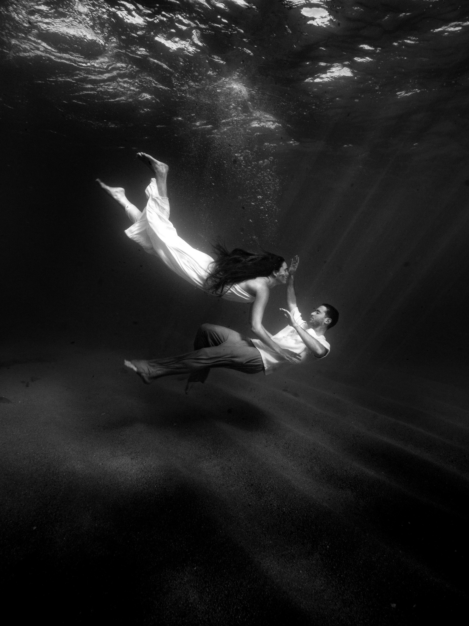 A black-and-white underwater portrait of a couple