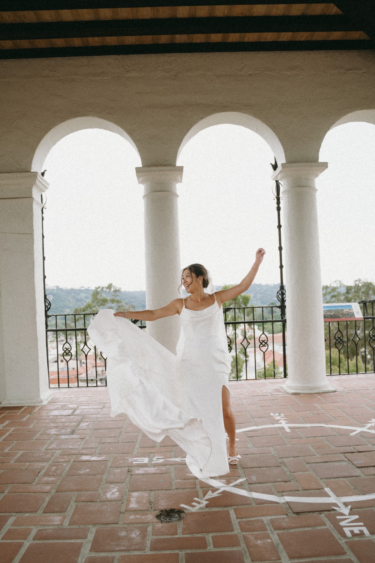 A bride dancing with her dress beneath the arches